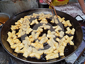 Merchants are frying chinese bread sticks for sale in the market.
