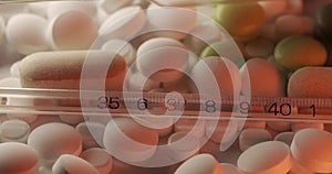 Mercury-in-glass thermometer on different white pills. Slim clinical thermometer under white and red light. Panning