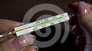 Mercury thermometer using animation shows temperature of 36.6 on woman hands during season of respiratory disease