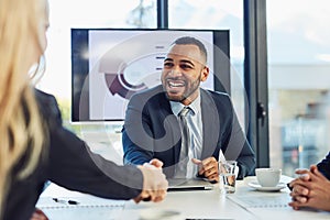 Merge and make it happen. a young businessman and businesswoman shaking hands during a meeting in a modern office.