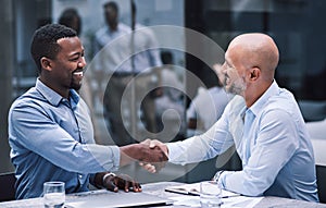 Merge with people who match your ambition. two businessmen shaking hands during a meeting.