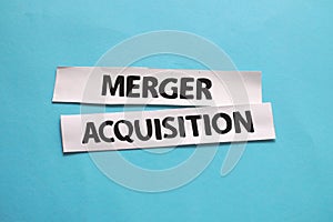 Merger and Acquisition, text words typography written on paper against blue background, life and business motivational