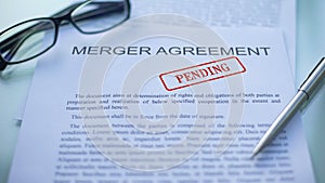 Merger agreement pending, officials hand stamping seal on business document