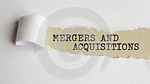 mergers and acquisitions. words. text on gray paper on torn paper background