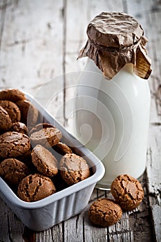 Meringue almond cookies in a bowl and bottle of milk