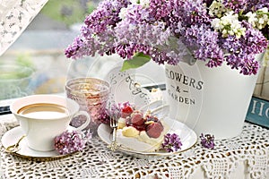 Meringue cake, coffee and bunch of purple lilacs on the windowsill photo