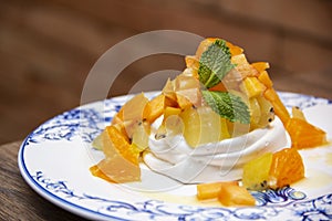 Meringue cake `Pavlova` with fresh yellow fruits and whipped cream