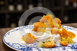 Meringue cake `Pavlova` with fresh yellow fruits and whipped cream