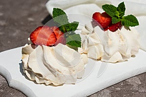 Meringue cake with strawberries on a white wooden board . Close-up