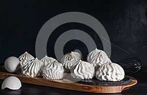 meringue and eggshell on wooden board on dark background. low kay, selective focus