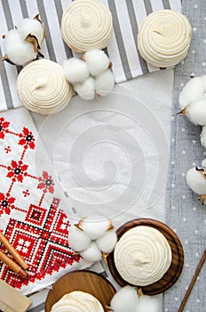 Meringue homemade zephyr in wooden tray, cotton buds and embroided napkin with traditional ornament. Mockup card. Template for