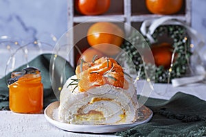 Meringue roll filled with mascarpone, cream and tangerine jam on a background of tangerines and a green heart.