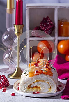 Meringue roll filled with mascarpone, cream and tangerine jam, decorated with tangerines and pomegranate seeds.