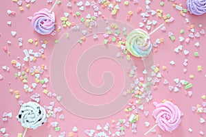 Meringues in pastel colors and scattered colorful on pink background.