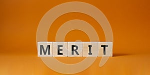 Merit symbol. Concept word Merit on wooden cubes. Beautiful orange background. Business and Merit concept. Copy space