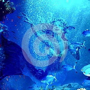Mermaid dive underwater through coral