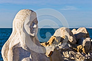 Mermaid sculpture carved out of the stone rocks at Piran harbor, Istria