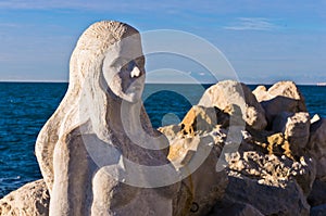 Mermaid sculpture carved out of the stone rocks at Piran harbor, Istria