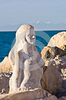 Mermaid sculpture carved out of the stone rocks at Piran harbor, Istria