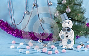 Merry adventures of a snowman under a green tree on new year`s eve on a blue decorated stage