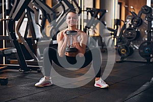 Cheerful young woman exercising buttocks in gym photo