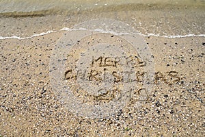 Merry Christmas 2019 written on tropical beach sand, copy space.