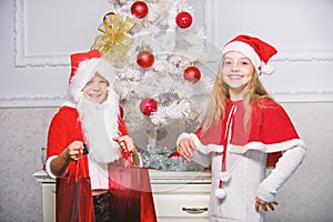 Merry christmas. Boy kid dressed as santa with white artificial beard and red hat give gift box to girl. Kids celebrate