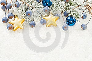 Merry Christmas card. Composition with green Xmas tree branch, blue berries and baubles on Xmas snow  background