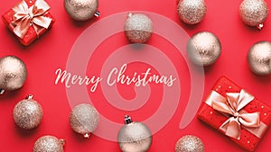 Merry Christmas card. Golden Christmas baubles and red gift boxes on red background in chaotic order, copy space. Minimal flat lay