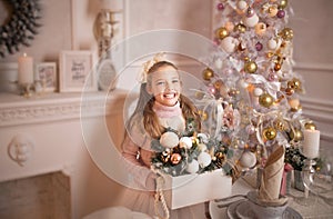 Merry Christmas celebration. Beautiful little girl in a dress lying near the Christmas tree. Winter holidays