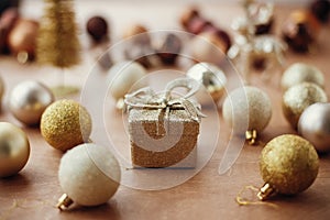 Merry Christmas. Christmas golden gift box on background of glitter tree and reindeer, shiny baubles and balls on rustic