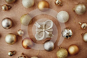 Merry Christmas. Christmas golden glitter gift box and shiny baubles and balls on rustic background, flat lay. Modern gold