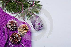 Merry Christmas composition. Flatlay of purple scarf, pine tree branch with silver toy, beads and painted cones. Copy space