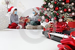 Merry christmas and coronavirus holidays, children with surgical masks exchange gift packages near the christmas tree, stay at