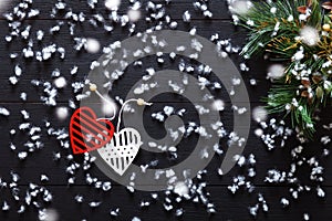 Merry Christmas decorations, snowflakes, white red hearts and green xmas tree on black wooden background card, top view