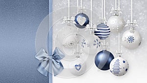 Merry Christmas decorative blue and white balls with shiny ribbons bows and glitter patterns, hanging on blurred lights snow