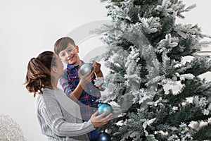 Merry christmas family at home, smiling brother and sister decorate the tree hang blue balls