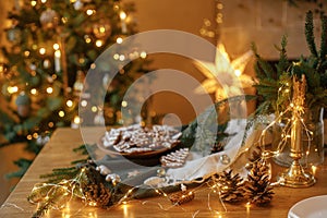 Merry Christmas! Festive decorations, candle, gingerbread cookies on wooden table with fir branches against christmas golden