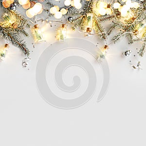 Merry Christmas garland with light on white background with silver decoration, fir branches, confetti, bokeh, light, glitter. Xmas