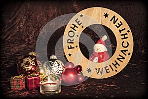 `Merry Christmas` in German with figure, Christmas tree balls and candle