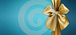 Merry christmas gift card , golden shiny ribbon bow isolated on turquoise glittering background, top view copy space template for