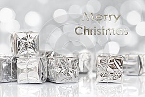Merry Christmas gifts in shiny silver paper, bokeh background