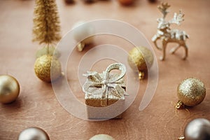 Merry Christmas. Christmas golden gift box on background of glitter tree and reindeer, shiny baubles and balls on rustic