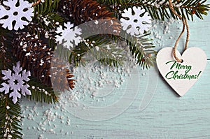 Merry Christmas greeting card.Decorative snowflakes,fir cones,heart and snowy fir tree branch on light blue background photo