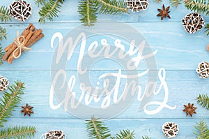 Merry Christmas greeting card with handwriting on rustic blue wooden background with christmas tree, cinnamone,anice photo