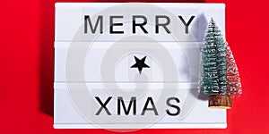 Merry Christmas greetings on lightbox on red with ornament tree