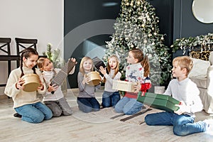 Merry Christmas. Group of children sitting in cozy room after exchanging Xmas presents at fun party