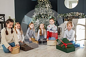 Merry Christmas. Group of children sitting in cozy room after exchanging Xmas presents at fun party