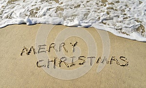 Merry Christmas handwritten in sand on beach