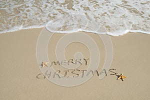 Merry Christmas handwritten in sand on beach